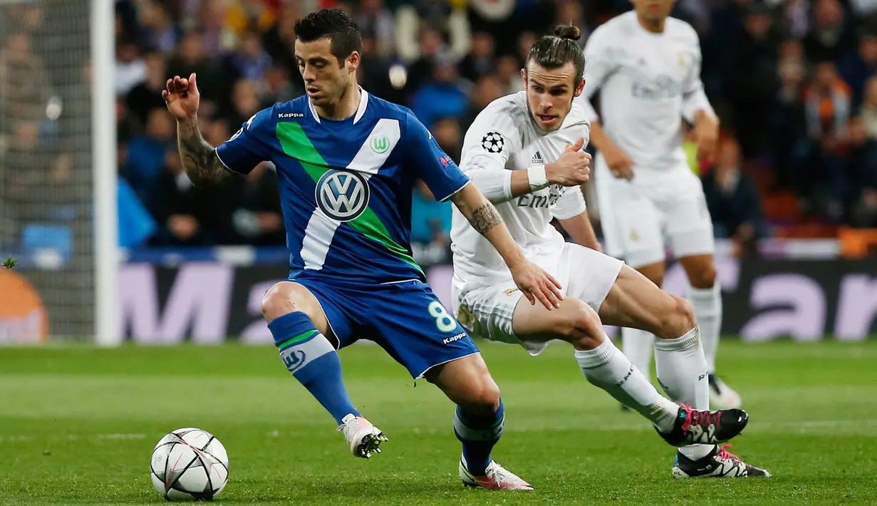 Gelandang Wolfsburg, Vieirinha (kiri) berusaha membawa bola dari kawalan gelandang Real Madrid, Gareth Bale di leg kedua liga Champions di Santiago Bernabeu, Spanyol (13/4). Madrid menang atas Wolfsburg dengan skor 3-0. (Reuters/Sergio Perez)