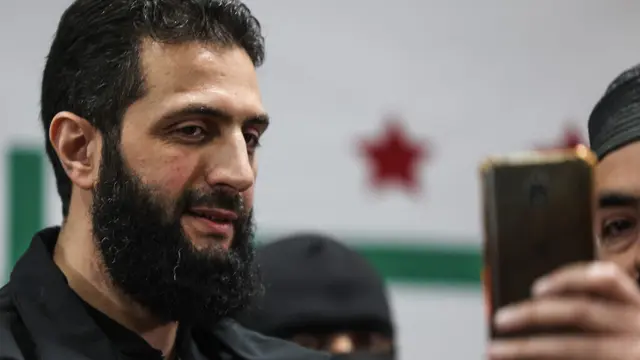 Abu Mohamed al-Golani, pimpinan Hayat Tahrir al-Sham (HTS), berpose selama konferensi pers di daerah Bab al-Hawa, Suriah, pada 12 Maret 2024.