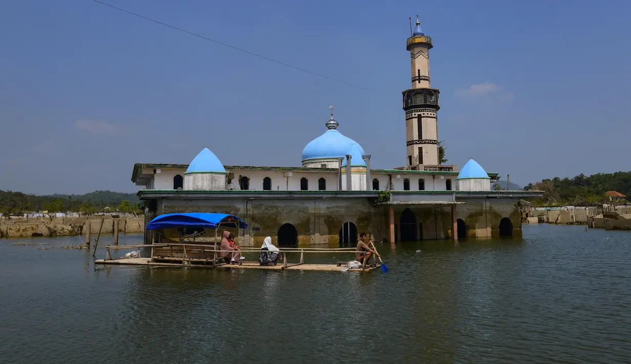 Warga menggunakan perahu  menyaksikan puing-puing bangunan mesjid dan rumah yang kembali muncul di kawasan Bendungan Karian yang mengering di Kampung Somang, Lebak, Banten, Jumat, 7 Agustus 2026. (KLY/ Arie Basuki)