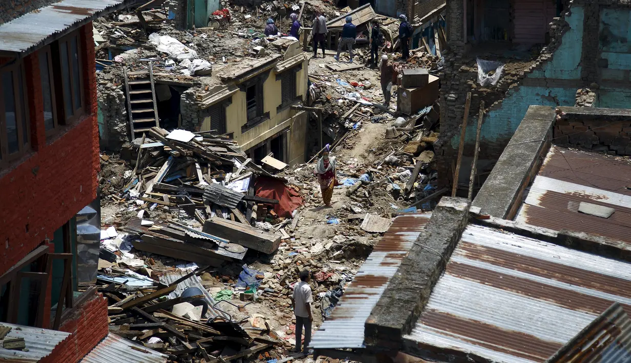 Sejumlah warga berjalan di reruntuhan puing bangunan pasagempa susulan berkekuatan 7,3 SR melanda Sankhu, Nepal, Selasa (12/5/2015). Sebelumnya, luka atas gempa dahsyat yang terjadi 25 April lalu di Nepal masih belum terobati. (REUTERS/Navesh Chitrakar)