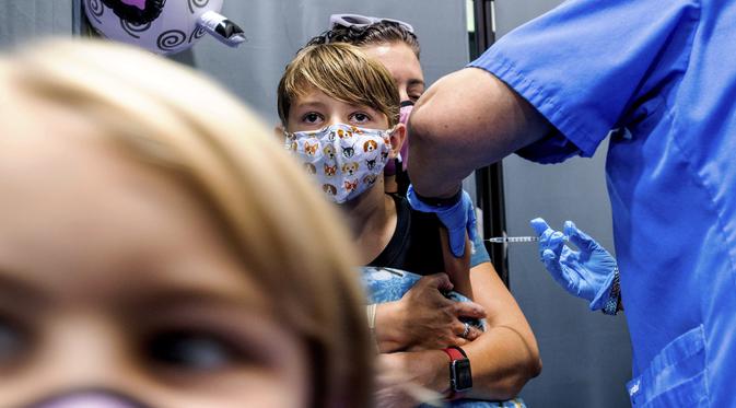 Finn Washburn (9) disuntik vaksin COVID-19 Pfizer-BioNTech saat adiknya, Piper Washburn (6) menunggu giliran saat vaksinasi anak 5 - 11 tahun di San Jose, California, Rabu (3/11/2021). Ini menjadi langkah perdana vaksinasi Covid-19 bagi anak kecil di Amerika Serikat. (AP Photo Noah Berger)
