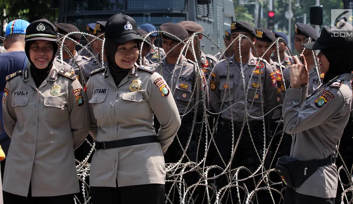 Aparat Polri wanita berpose saat berjaga pendemo memperingati Hari Buruh Sedunia di depan Istana Negara, Jakarta, Selasa (1/5). Memperingati Hari Buruh 2018, ribuan buruh mulai memadati Istana Kepresidenan, Jakarta Pusat. (Liputan6.com/Johan Tallo)