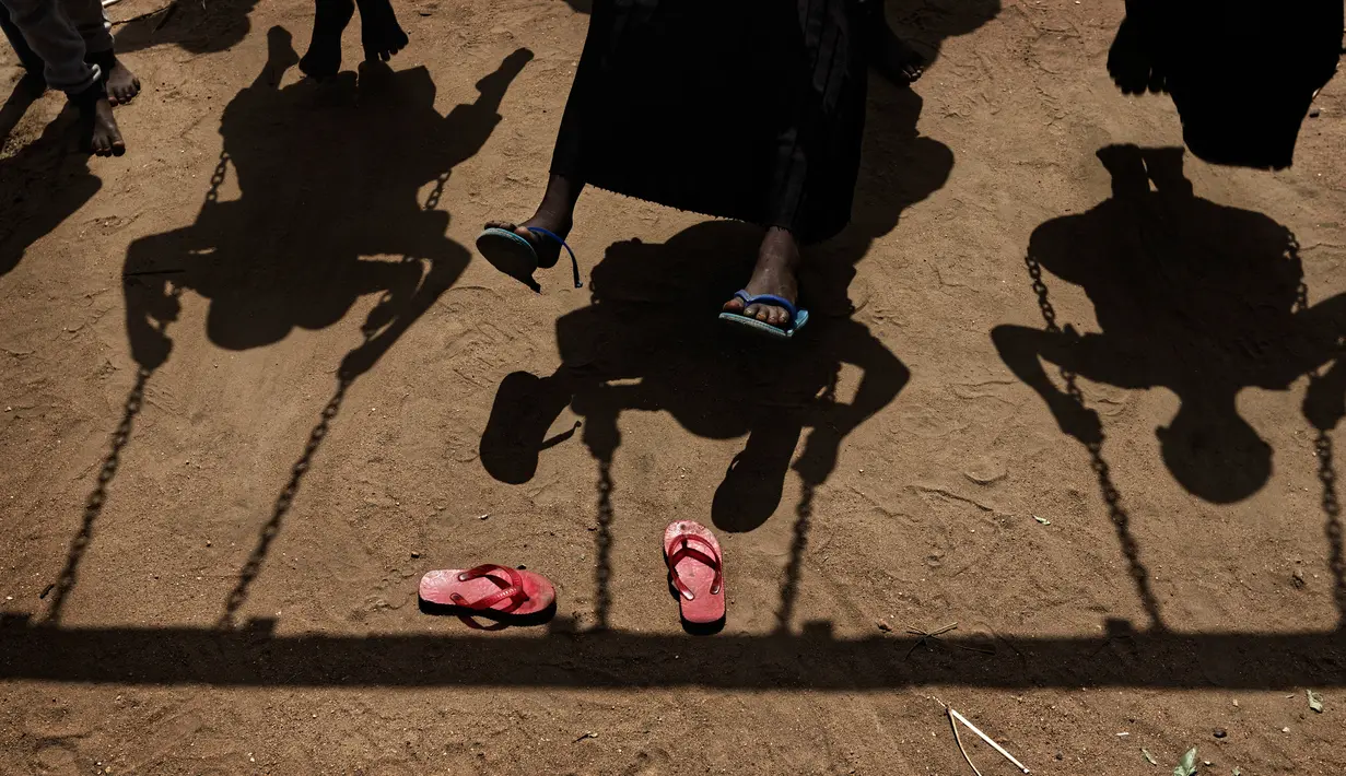 Anak-anak pengungsi Sudan Selatan bermain ayunan saat istirahat makan siang di halaman sekolah pembibitan Ombechi di Bidi Bidi, Uganda, (5/6). Sekolah ini dukung oleh UNICEF dan Save the Children yang memiliki lebih dari 500 murid. (AP Photo/Ben Curtis)