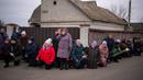 Para pelayat berlutut menunggu peti mati Oleksandr Maksymenko (38) lewat saat pemakamannya di kampung halamannya di Kniazhychi, sebelah timur Kyiv, Ukraina, 13 Februari 2023. Oleksandr Maksymenko, seorang warga sipil yang menjadi sukarelawan di angkatan bersenjata Ukraina, tewas dalam pertempuran di daerah Bakhmut. (AP Photo/Emilio Morenatti)
