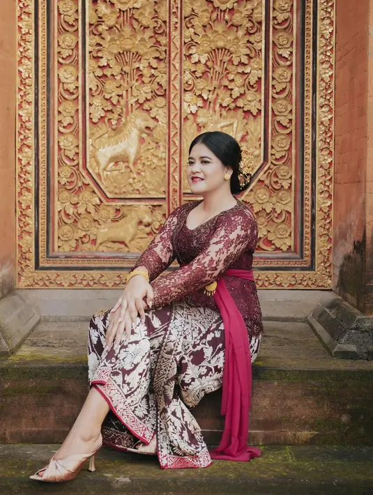 Kahiyang dengan kebaya Bali, anggun berpose di depan pintu rumah khas Bali. Kali ini, Kahiyang mengenakan kebaya rancangan Desak Made Arisanthi Dewi berwarna ungu wine yang cantik. Penampilannya dilengkapi dengan kain tradisional tenun Bali dan selendang bernuansa senada. Foto: Instagram.