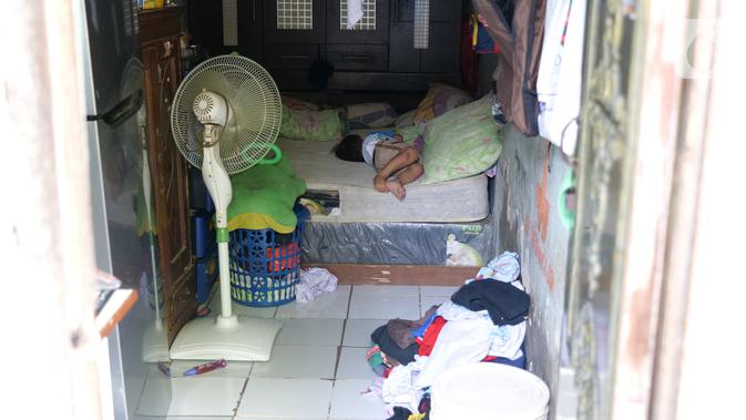 Seorang anak tidur di dalam rumahnya di Gang Sekretaris, RT 015/RW 007 Tanjung Duren Utara, Jakarta Barat , Selasa (8/10/2019). Warga di kawasan ini tak memiliki septic tank sehingga hajat yang dibuang langsung mengalir ke kali yang bersebelahan dengan tempat tinggal. (Liputan6.com/Herman Zakharia)
