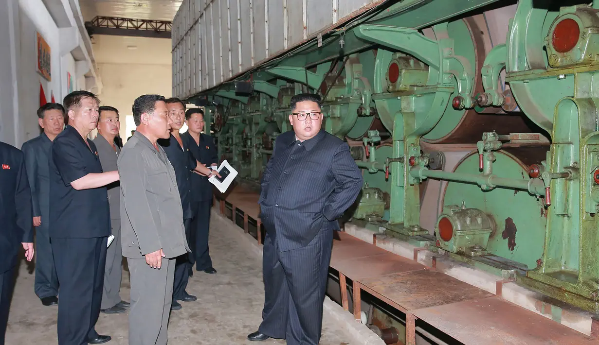 Pemimpin Korea Utara, Kim Jong-un berbincang saat meninjau Sinuiju Chemical Fiber Mill di Sinuiju, Korea Utara (2/7). (AFP Photo/KCNA Via KNS)