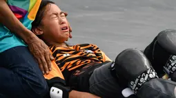 Tim medis melakukan pertolongan kepada skateboarder Malaysia Christina Grace Lai yang cedera saat melakukan pemanasan jelang final taman putri Asian Games 2018 di Palembang, Rabu (29/8). Atlet 13 tahun itu terjatuh saat  melakukan trik. (Mohd RASFAN/AFP)