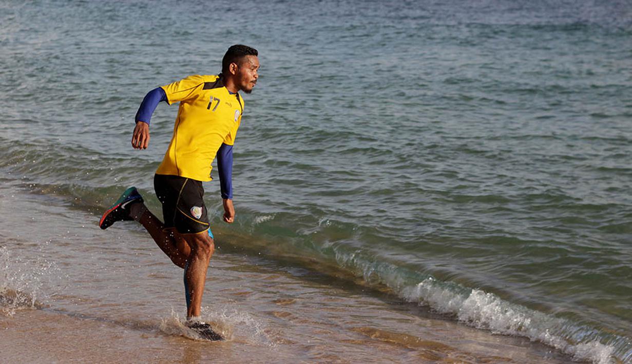 Bek sayap Arema Cronus, Hasim Kipuw, menikmati latihan fisik di Pantai Balekambang, Malang. (Bola.com/Kevin Setiawan)