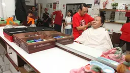 Mantan Menko Bidang Kemaritiman Rizal Ramli saat mencukur rambut di kawasan Glodok, Jakarta Barat, Kamis (15/2). Rizal menembus lorong yang tergenang air dan berdialog dengan pedagang. (Liputan6.com/Pool/Yasin)
