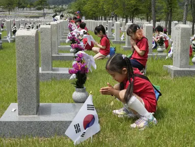 Murid-murid taman kanak-kanak berdoa di depan nisan tentara yang gugur selama Perang Korea 1950-1953 pada malam Memorial Day Korea Selatan di Pemakaman Nasional, Seoul, Korea Selatan, Senin (5/6/2023). Memorial Day di Korea Selatan diperingati setiap tanggal 6 Juni tiap tahunnya. (AP Photo/Ahn Young-joon)