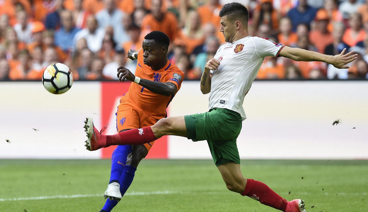 Pemain Belanda, Georgina Wijnaldum (kiri) melepaskan tembakan melewati adangan pemain Bulgaria, Strahil Popov pada laga grup A kualifikasi Piala Dunia 2018 di Amsterdam, (3/9/2017). Belanda menang 3-1. (AFP/John Thys)