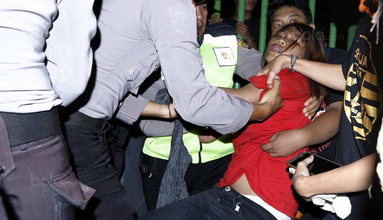 Polisi menolong Jakmania yang pingsan saat berdesakan masuk stadion Patriot, Minggu (12/11/2017). Pertandingan terakhir Persija di Liga 1 2017 ini membuat antusias Jakmania semakin tinggi untuk datang menyaksikan laga. (Bola.com/ M Iqbal Ichsan)