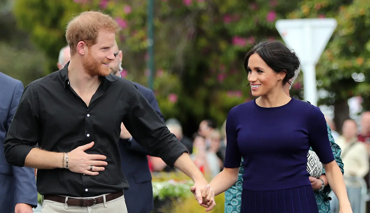 Pangeran Harry dan Meghan Markle berjalan di Taman Pemerintah Rotorua, Selandia Baru, Rabu (31/10). Pangeran Harry dan Meghan Markle sedang dalam tur tiga minggu di Australia, Selandia Baru, Tonga, dan Fiji. (Michael Bradley/Pool/AFP)