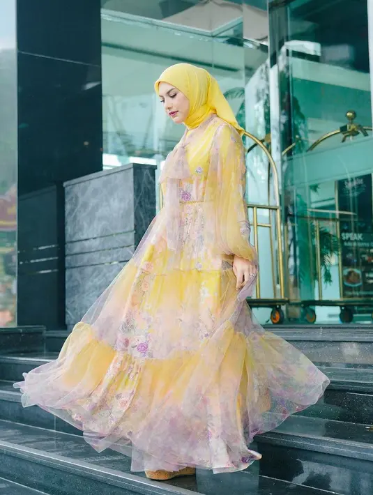 Irish Bella dengan dress panjang bernuansa kekuningan. Dress ini memiliki motif flora yang cantik, dipadunya dengan hijab kuning polos yang serasi. [Foto: Instagram/_irishbella_]