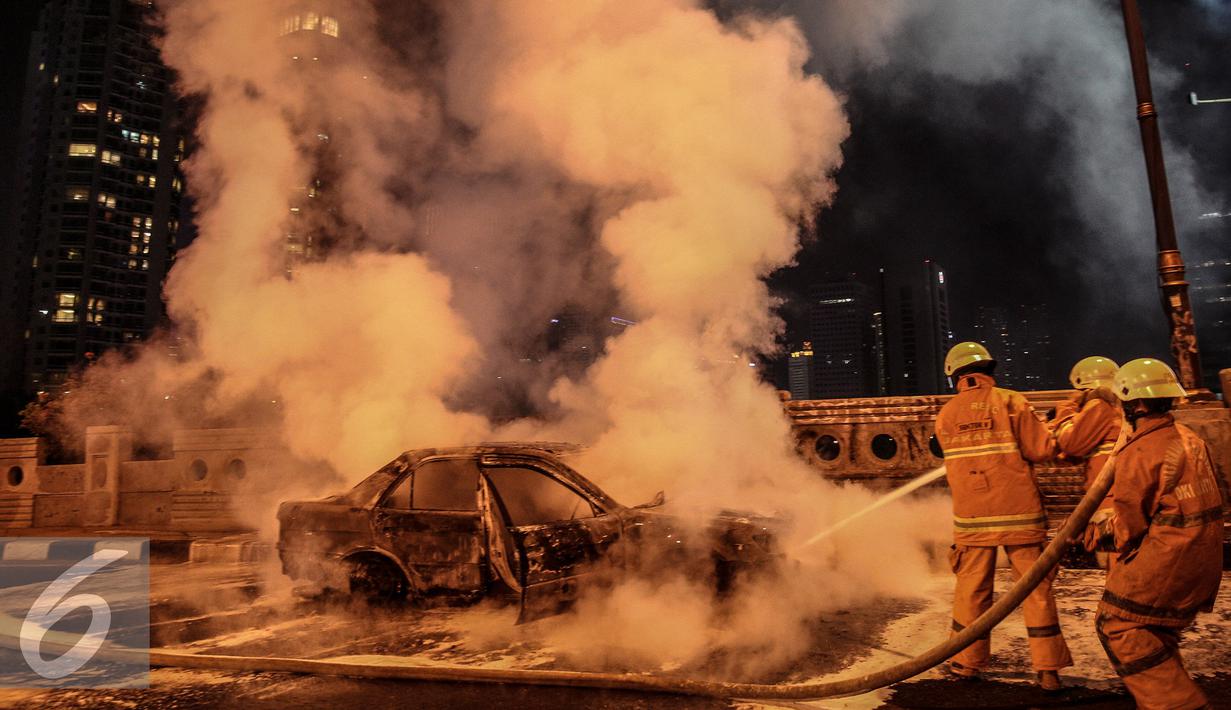 Petugas berusaha memadamkan api mobil yang terbakar di jalan layang Latuharhari, Jakarta, Kamis (18/9/2015). Diduga kebakaran akibat konsleting listrik yang terjadi dibagian depan kap mobil. (Liputan6.com/Faizal Fanani)