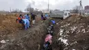 Sejumlah jenazah dimasukkan ke dalam kuburan massal di pinggiran Mariupol, Ukraina, 9 Maret 2022. Warga tidak dapat menguburkan orang mati di antara mereka karena serangan berat oleh pasukan Rusia. (AP Photo/Evgeniy Maloletka)