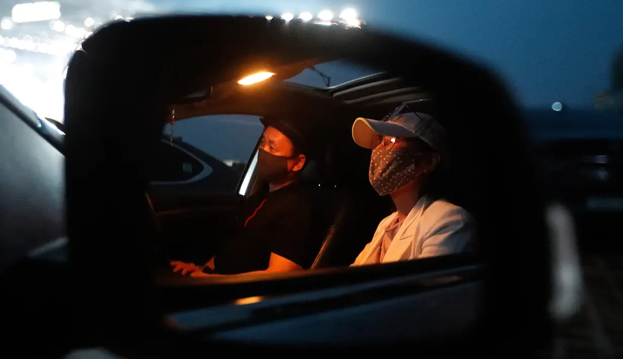 Orang-orang duduk di dalam mobil sambil menyaksikan konser drive-in Stage X di sebuah tempat parkir di Goyang, pada 23 Mei 2020. Tujuan konser ini untuk memberikan hiburan bagi warga Korea Selatan yang mendambakan acara-acara musik yang ditangguhkan selama pandemi Covid-19. (AP Photo/Ahn Young-joo)