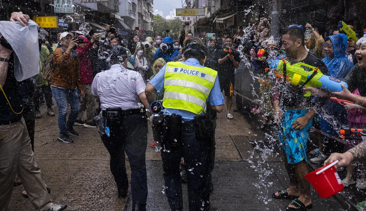 Orang-orang yang bersuka ria memercikkan air ke petugas polisi saat perayaan festival Songkran di Hong Kong, Minggu, 9 April 2023. (AP Photo/Louise Delmotte)