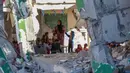 Foto yang dipublikasikan pada 4 Desember 2024 menunjukkan seorang guru Palestina, Doha al-Attar (30) saat memberi pelajaran kepada anak-anak di sebuah ruang kelas yang rusak parah di Khan Yunis, wilayah selatan Jalur Gaza. (Bashar TALEB/AFP)