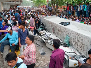 Warga India berkumpul untuk menyaksikan lokasi runtuhnya material jalan layang di kota Varanasi, Selasa (15/5). Sedikitnya 18 orang tewas dan belasan orang terperangkap setelah jembatan layang roboh dan menghancurkan kendaraan di bawahnya. (AP Photo)