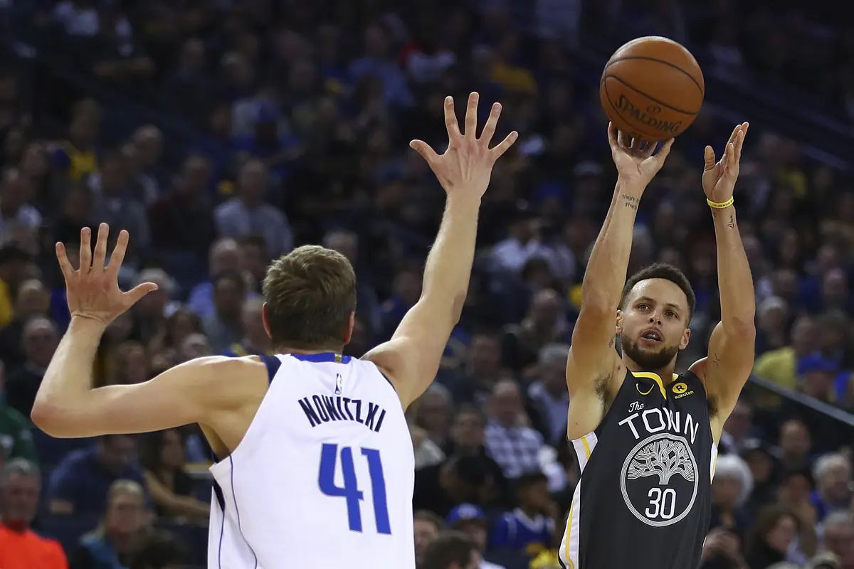Stephen Curry (hitam) melepaskan tembakan saat Warriors menghajar Mavericks