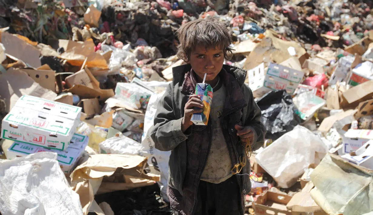 Seorang bocah laki-laki minum jus kadaluwarsa dari tumpukan sampah di sebuah tempat pembuangan akhir (TPA) di pinggiran Sanaa, Yaman, Rabu (16/11). Setiap hari para bocah di daerah itu mengumpulkan sampah untuk didaur ulang. (REUTERS/Mohamed al-Sayaghi)