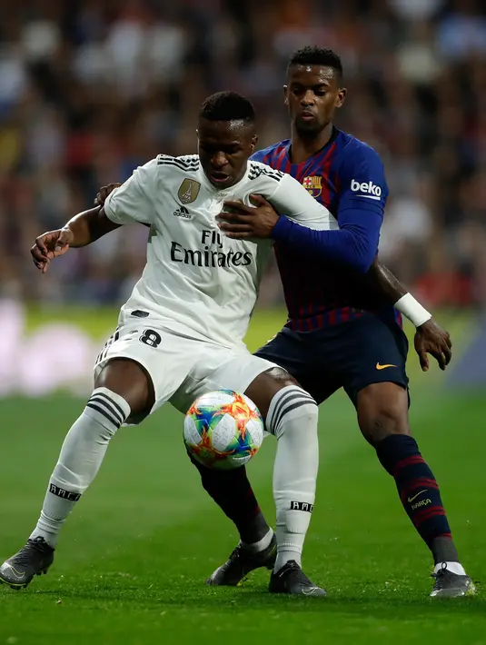 Penyerang Real Madrid, Vinicius Junior berebut bola dengan bek Barcelona, Nelson Semedo pada laga leg kedua semifinal Copa del Rey di Stadion Santiago Bernabeu, Rabu (27/2). Barcelona merebut tiket final Copa del Rey usai menang 3-0. (AP/ Manu Fernandez)