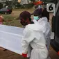Petugas mengangkat peti jenazah Covid-19 untuk dimakamkan dengan prosedur covid 19 di TPU Tegal Alur, Jakarta, Minggu (3/12/2021). Sebanyak 625.518 kasus dinyatakan sembuh dan 22.555 orang meninggal dunia. (Liputan6.com/Angga Yuniar)
