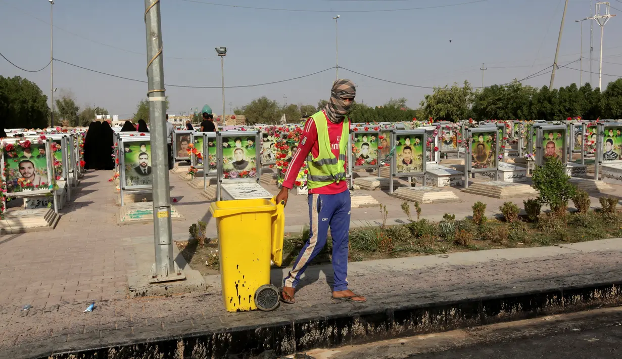 Seorang pekerja menarik tempat sampah di pemakaman Wadi al-Salam, di Najaf, selatan Baghdad, Irak, 5 Agustus 2016. Jumlah kuburan terus bertambah setiap tahunnya, sejak perang Irak 2004 silam. (REUTERS/Alaa Al-Marjani)