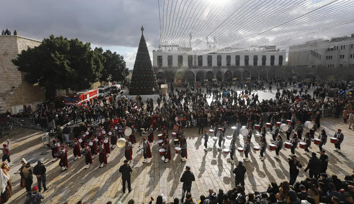 Pramuka Palestina berparade melalui Manger Square di Church of the Nativity, yang secara tradisional diyakini sebagai tempat kelahiran Yesus Kristus, selama perayaan Natal, di kota Betlehem, Tepi Barat, Jumat (24/12/2021). (AP Photo/Mahmoud Illean)