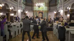 Pria menari selama hari libur Yahudi Hanukkah di Sinagoga di Vilnius, Lithuania, Minggu (28/11/2021). Perayaan tahunan komunitas malam pertama Hanukkah kembali dengan kapasitas penuh tahun ini setelah perayaan dibatasi pada tahun 2020 karena pandemi virus corona. (AP Photo/Mindaugas Kulbis)