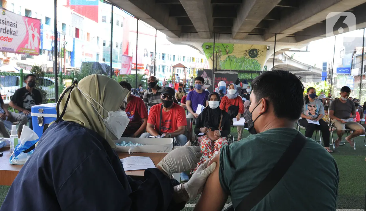 Petugas kesehatan menyuntikkan vaksin dosis ketiga kepada seorang pria di kolong flyover Ciputat, Tangerang Selatan, Sabtu (2/4/2022). Selain untuk melengkapi vaksin COVID-19, booster menjadi syarat perjalanan mudik lebaran tahun 2022. (merdeka.com/Arie Basuki)