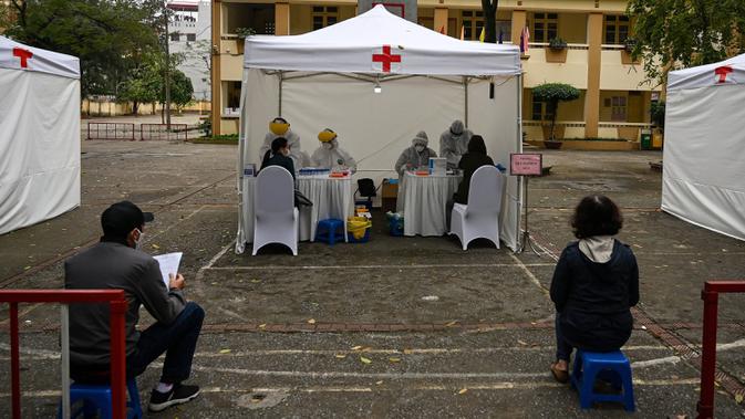 Penduduk memakai masker mengantre dengan tertib saat akan mengikuti pengujian Covid-19 di pusat pengujian darurat di Hanoi, Vietnam (31/3/2020). Di pusat pengujian darurat ini petugas menyediakan fasilitas bangku kecil yang diberi jarak untuk pencegahan Covid-19. (AFP/Manan Vatsyayana)