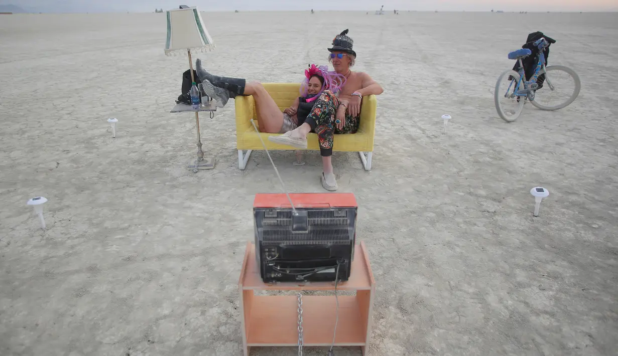 Jody Friedman dan Jeff Montgomery mengeksplorasi karya seni dengan cara menonton televisi di Festival Burning Man, di padang pasir Black Rock, Nevada, Amerika Serikat (30/08). (REUTERS/Jim Urquhart)