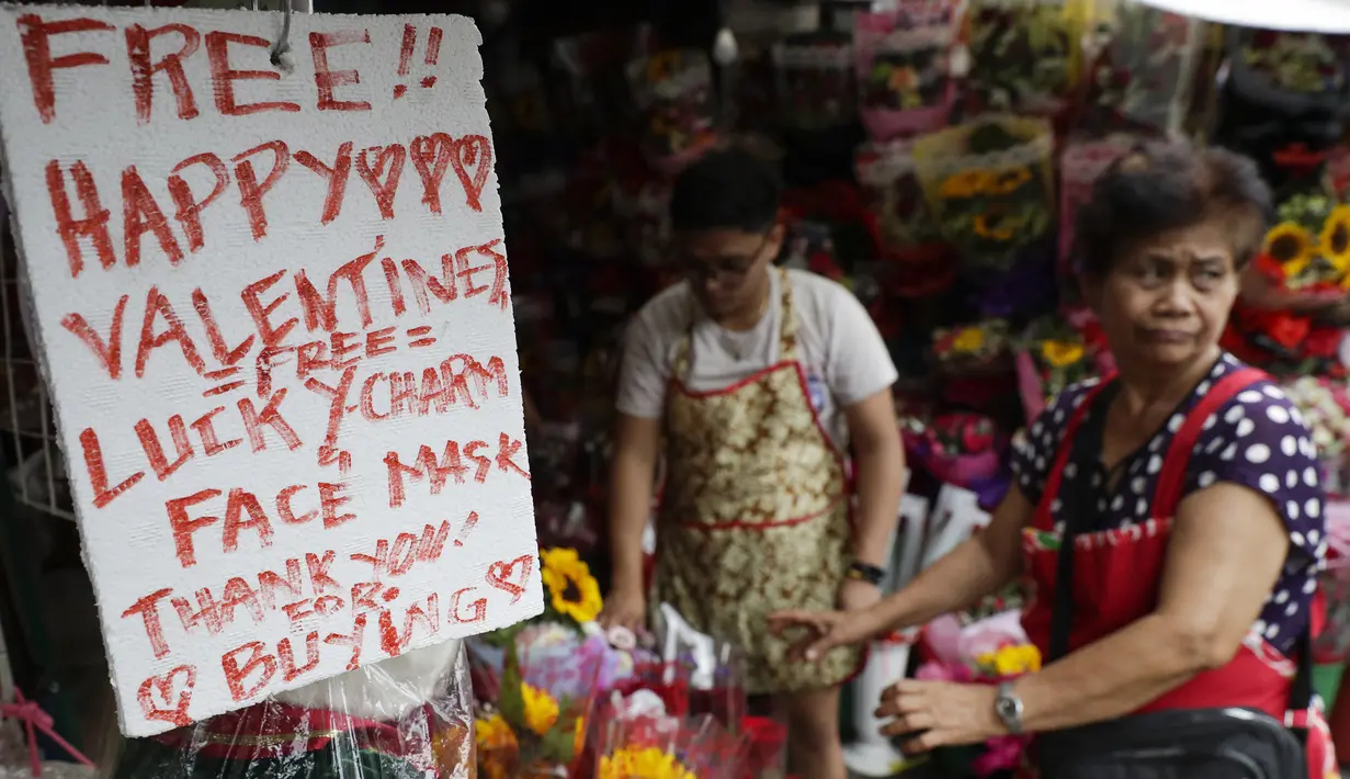Toko bunga menawarkan pesona keberuntungan dan masker wajah gratis sebagai bagian dari promosi Hari Kasih Sayang di Alabang, Manila, Filipina (13/2/2020). (AP Photo/Aaron Favila)