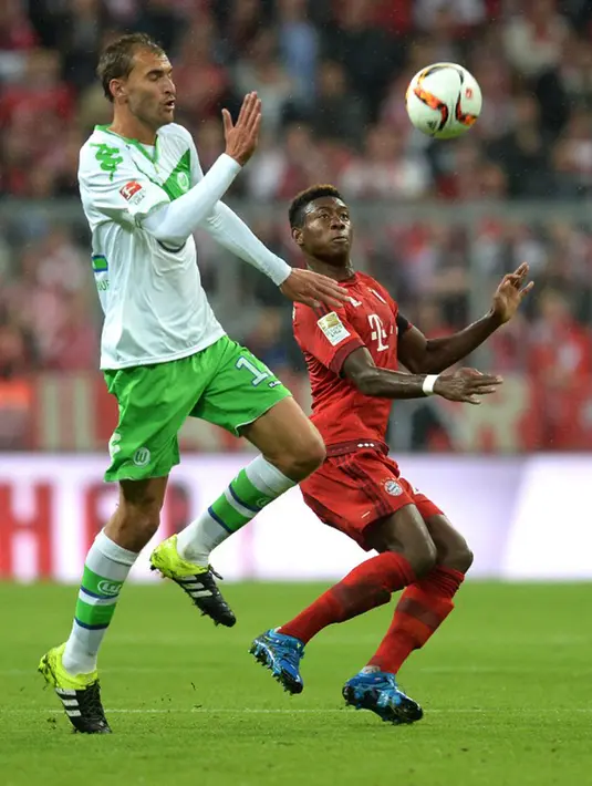 Bek Muenchen, David Alaba (kanan) berebut bola dengan penyerang Wolfsburg, Bas Dost pada bundesliga di Allianz Arena, Rabu (23/9/2015). Muenchen menang telak atas Wolfsburg dengan skor 5-1. (AFP PHOTO/Christof Stache)