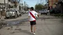 Daniel Dorado dari Argentina mengenakan jersey River Plate berjalan pulang ke rumahnya di daerah kumuh Costa Eperanza, Buenos Aires, 12 September 2020. Daniel, 12, yang bersekolah di sekolah sepak bola Angel Labruna bermimpi menjadi pemain divisi pertama di klub River Plate. (ARIEL TIMY TORRES/AFP)