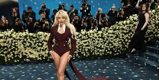 Sabrina Carpenter mengenakan Louis Vuitton karya Direktur Kreatif Pria Pharrell Williams ke Met Gala 2025. Siluet yang dibuat khusus terdiri dari jas berekor yang memanjang yang dibuat dari wol jacquard bergaris-garis merah dengan kancing kristal, dan korset yang dibentuk dari kain yang sama. Dipakai dengan kerah kemeja putih yang dikanji tinggi. Ia tampil dengan inner jumpsuit pantsless. [dok. Louis Vuitton]