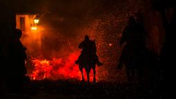Seorang pria menunggang kuda melintasi kobaran api dalam tradisi tahunan Luminarias memperingati Hari Santo Anthony (santo pelindung hewan) di San Bartolome de Pinares, Spanyol, 16 Januari 2023. Tradisi yang sudah berlangsung selama 500 tahun ini dilakukan sebagai upaya 'pemurnian' hewan dengan cara melintasi kobaran api. (AP Photo/Manu Fernandez)
