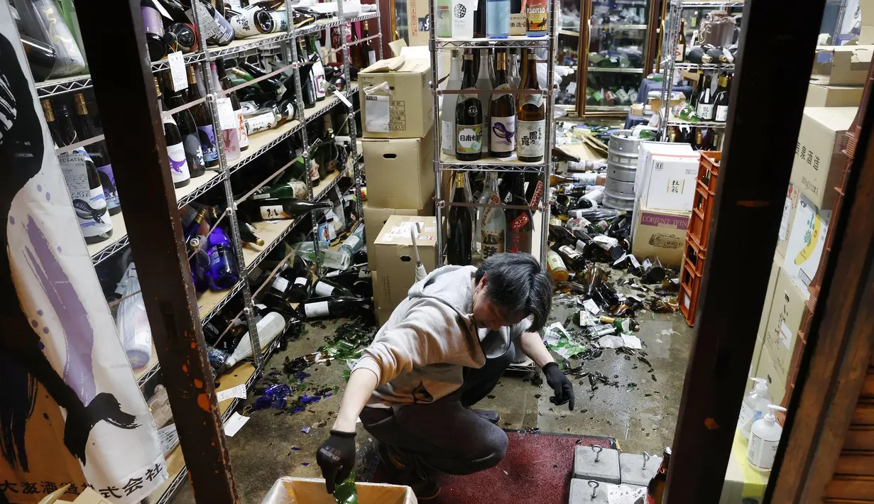 Manajer toko minuman keras membersihkan botol yang rusak setelah gempa bumi di Fukushima, timur laut Jepang, Sabtu (13/2/2021). Pusat gempa berada di kedalaman 60 kilometer lepas pantai Prefektur Fukushima, pada pukul 23.08 waktu setempat. (Jun HIrata/Kyodo News via AP)