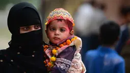 Seorang wanita Muslim India bersama anaknya yang menderita cerebral palsy ambil bagian dalam acara festival Hindu Holi untuk anak-anak dengan cerebral palsy yang diselenggarakan oleh Yayasan Trishla di Allahabad (25/2). (AFP Photo/Sanjay Kanojia)