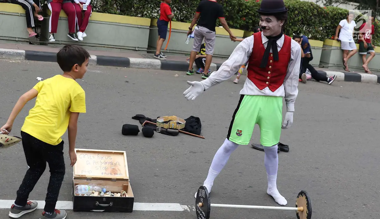 Seniman pantomin menyapa seorang anak saat car free day di Jakarta, Minggu (1/7). Aksi tersebut dilakukan guna mengumpulkan biaya yang akan digunakan untuk menikah. (Liputan6.com/Immanuel Antonius)