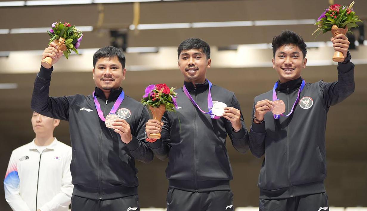 Selebrasi tim menembak beregu putra Indonesia (dari kiri) Irfandi Julio, Muhammad Sejahtera Dwi Putra dan Muhammad Badri Akbar dengan medali perunggu di atas podium usai menempati peeringkat ketiga nomor 10 meter running target beregu putra cabang menembak Asian Games Hangzhou 2022 di Fuyang Yinhu Sports Centre, Hangzhou, China, Senin (25/9/2023). (NOC Indonesia)