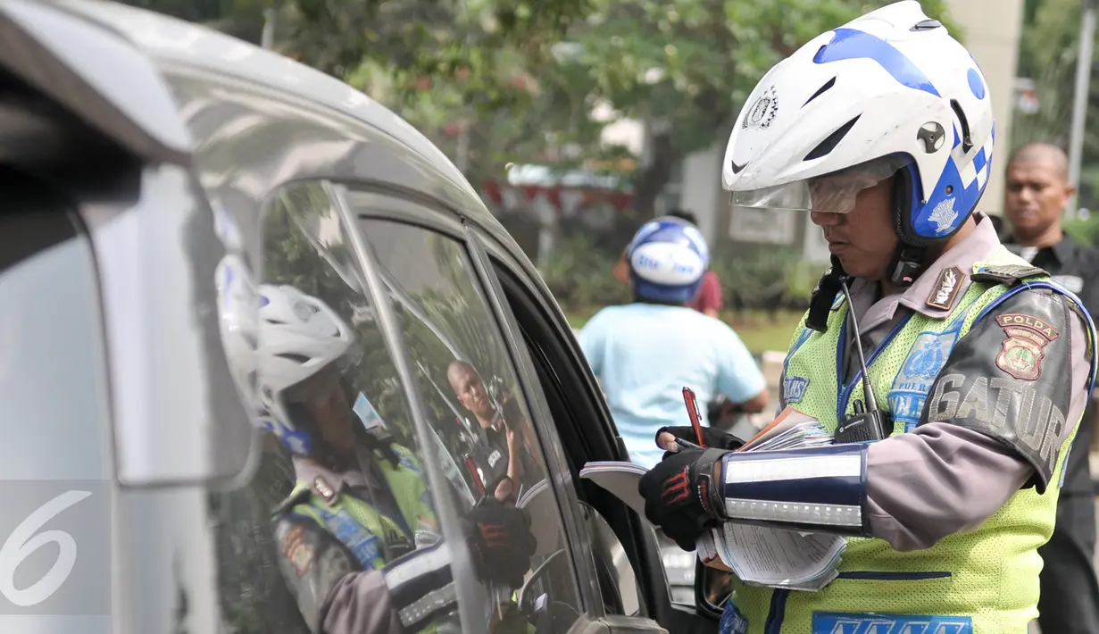Petugas menilang pengendara mobil yang melanggar aturan pembatasan kendaraan sistem ganjil genap di kawasan Sudirman, Jakarta, Selasa (30/8). Hari ini resmi diberlakukan denda bagi pelanggar aturan sistem ganjil genap. (Liputan6.com/Yoppy Renato)
