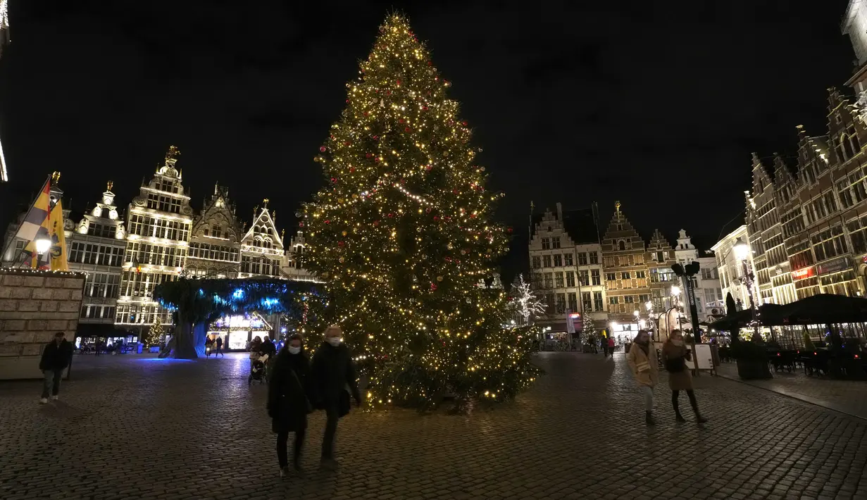 Orang-orang berjalan di sebelah pohon Natal dan dekorasi lainnya di pusat bersejarah Antwerpen, Belgia, 20 Desember 2021. Negara-negara di Eropa mempertimbangkan pembatasan yang lebih ketat guna membendung gelombang baru infeksi COVID-19 yang didorong oleh varian omicron. (AP Photo/Virginia Mayo)