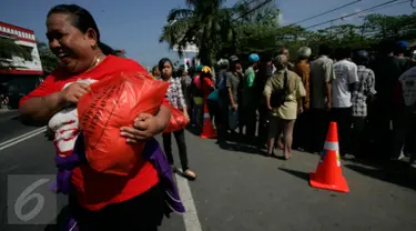 Seorang warga membawa sembako yang dibagikan oleh Presiden Joko Widodo atau Jokowi di halaman Gedung Graha Saba, Solo, Jawa Tengah, Jumat (8/7). Keluarga Jokowi membagikan 2.200 paket sembako kepada warga Solo. (Liputan6.com/Boy Harjanto)