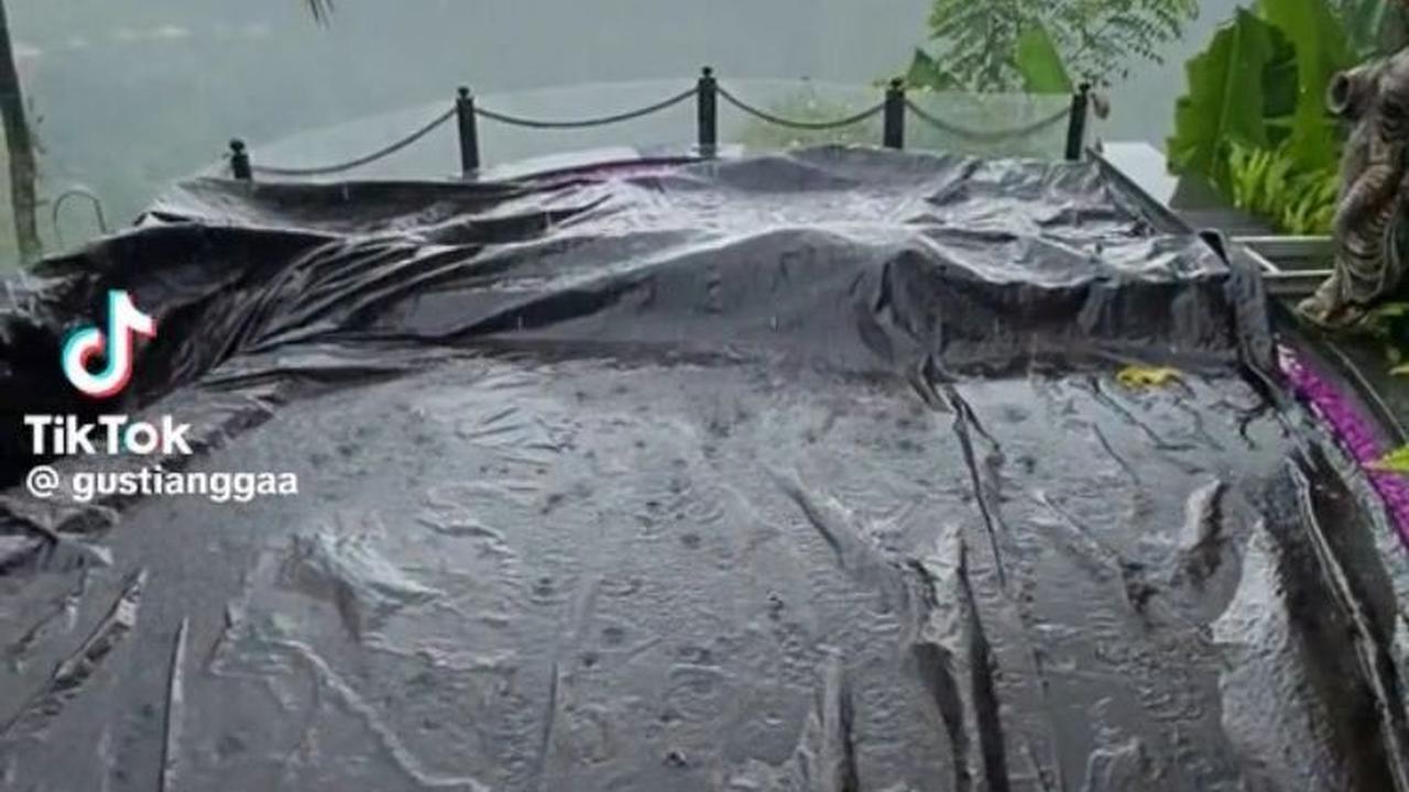 Namun siapa sangka, tiba-tiba hujan yang awalnya hanya gerimis berubah menjadi deras. Akhirnya, mau tidak mau mereka pun harus melindungi kolam renang dengan terpal.