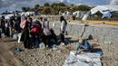 Para migran mengumpulkan air sementara yang lain membersihkan barang-barang mereka setelah hujan badai di kamp pengungsi Kara Tepe, di pulau Lesbos di timur laut Aegean, Yunani (14/10/2020).  (AP Photo/Panagiotis Balaskas)