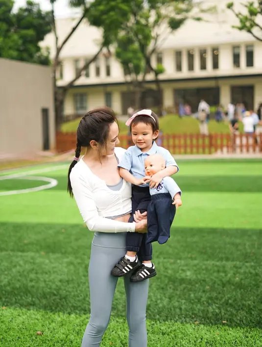Shandy tampak memadukan crop top dengan celana legging panjang. Sambil menggendong Claire, ia memperlihatkan tubuhnya yang semakin langsing. (Instagram/shandyaulia).